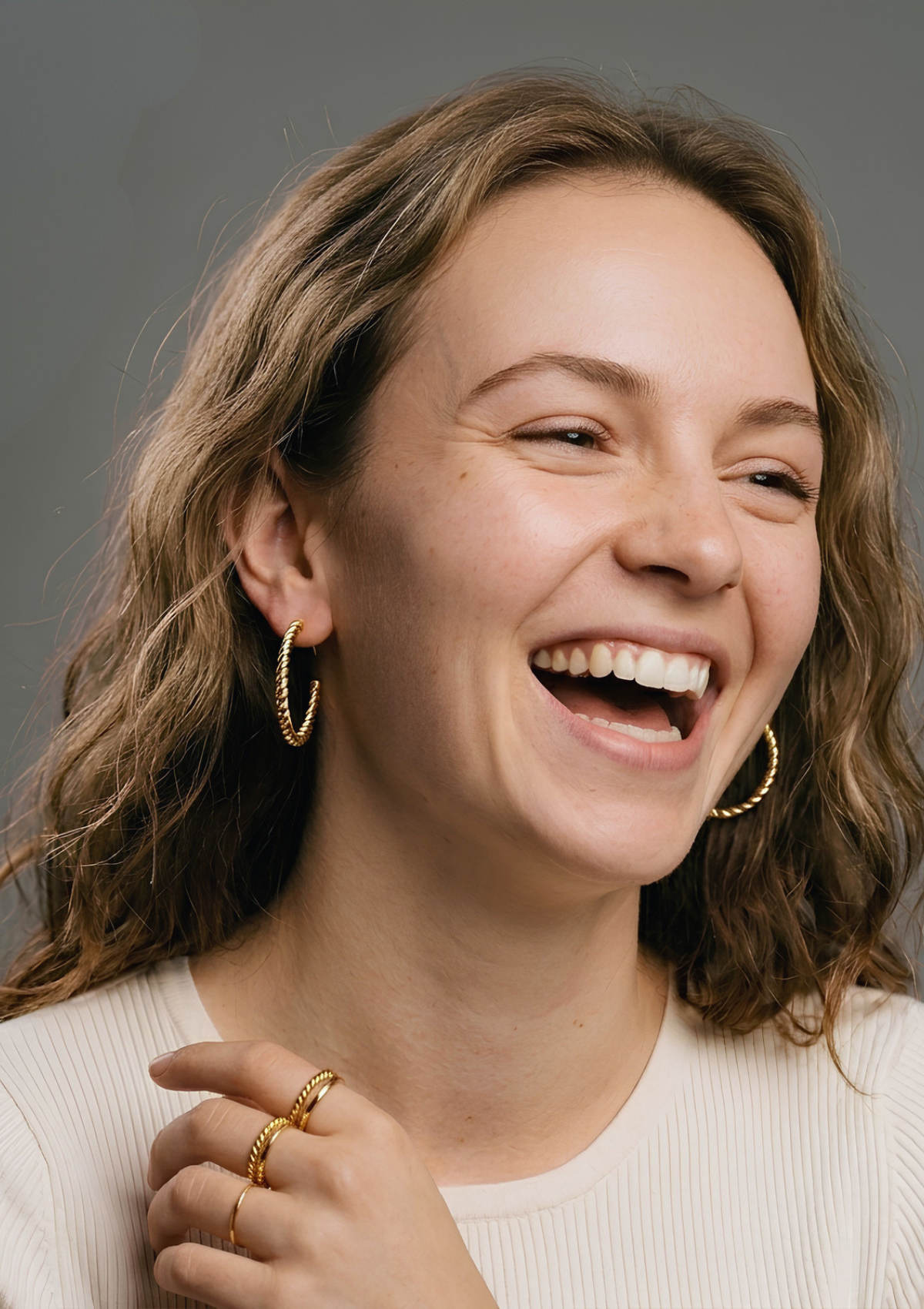 Woman wearing gold rope hoop earrings and stacked gold rings, Vampa Amsterdam fine jewellery