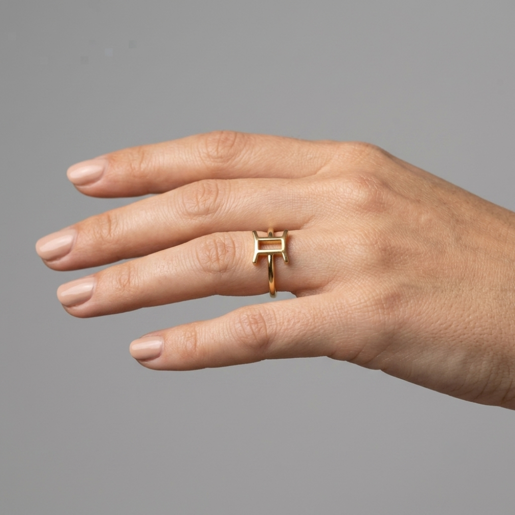 Model wearing Gemini gold ring, editorial close-up on deep charcoal background