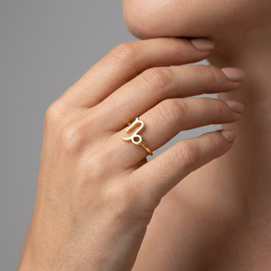Model wearing Capricorn zodiac gold ring on ring finger, close-up hand shot