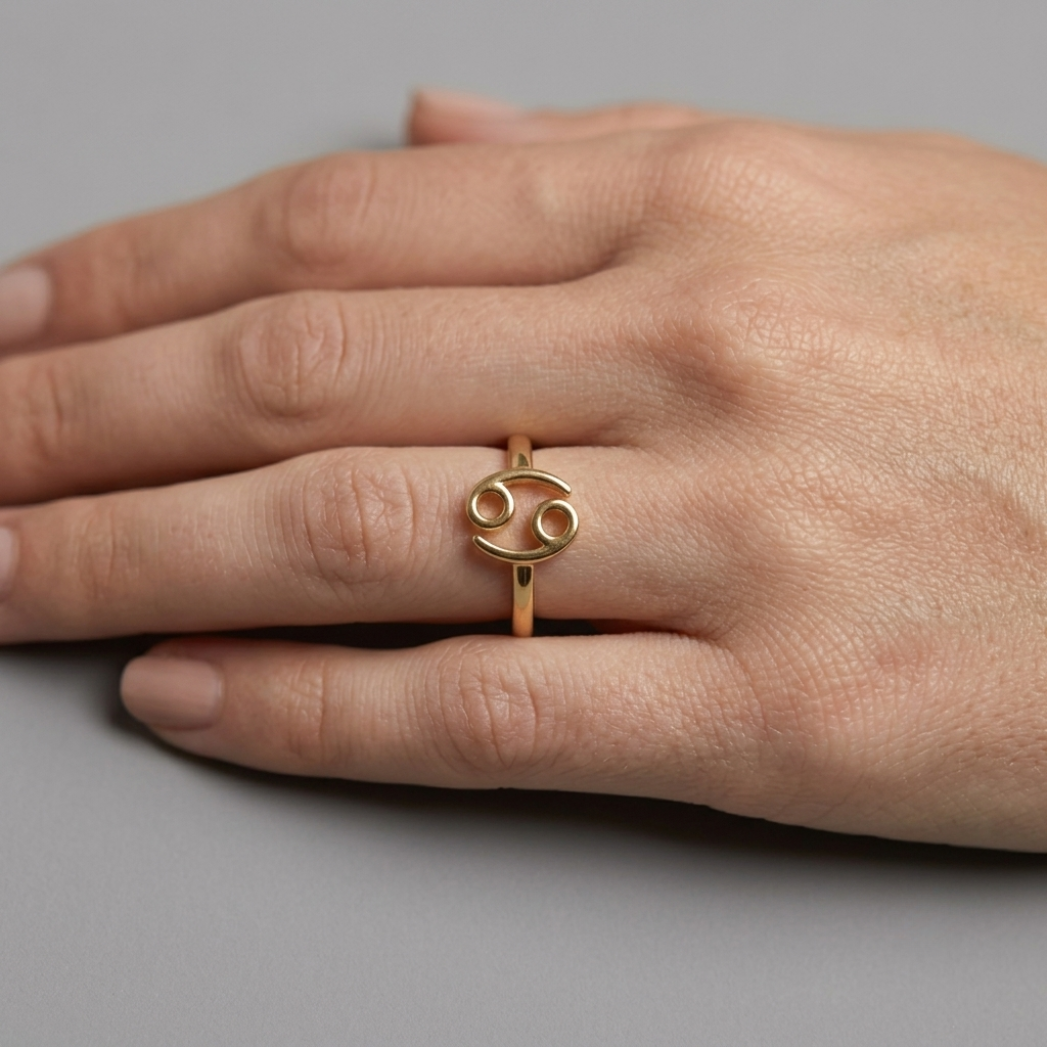 Model wearing Cancer zodiac gold ring on ring finger, close-up hand shot