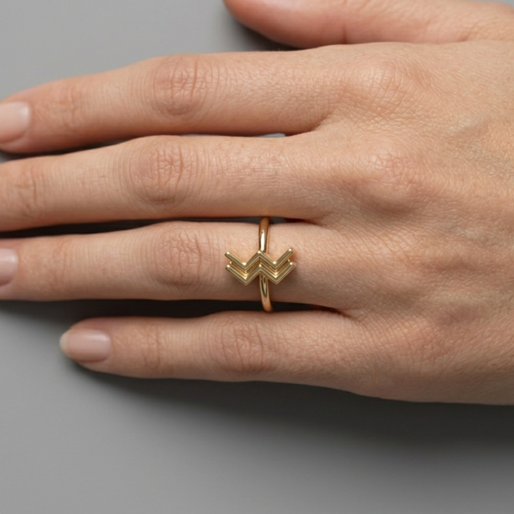 Model's hand resting on fabric wearing Aquarius zodiac ring, soft daylight