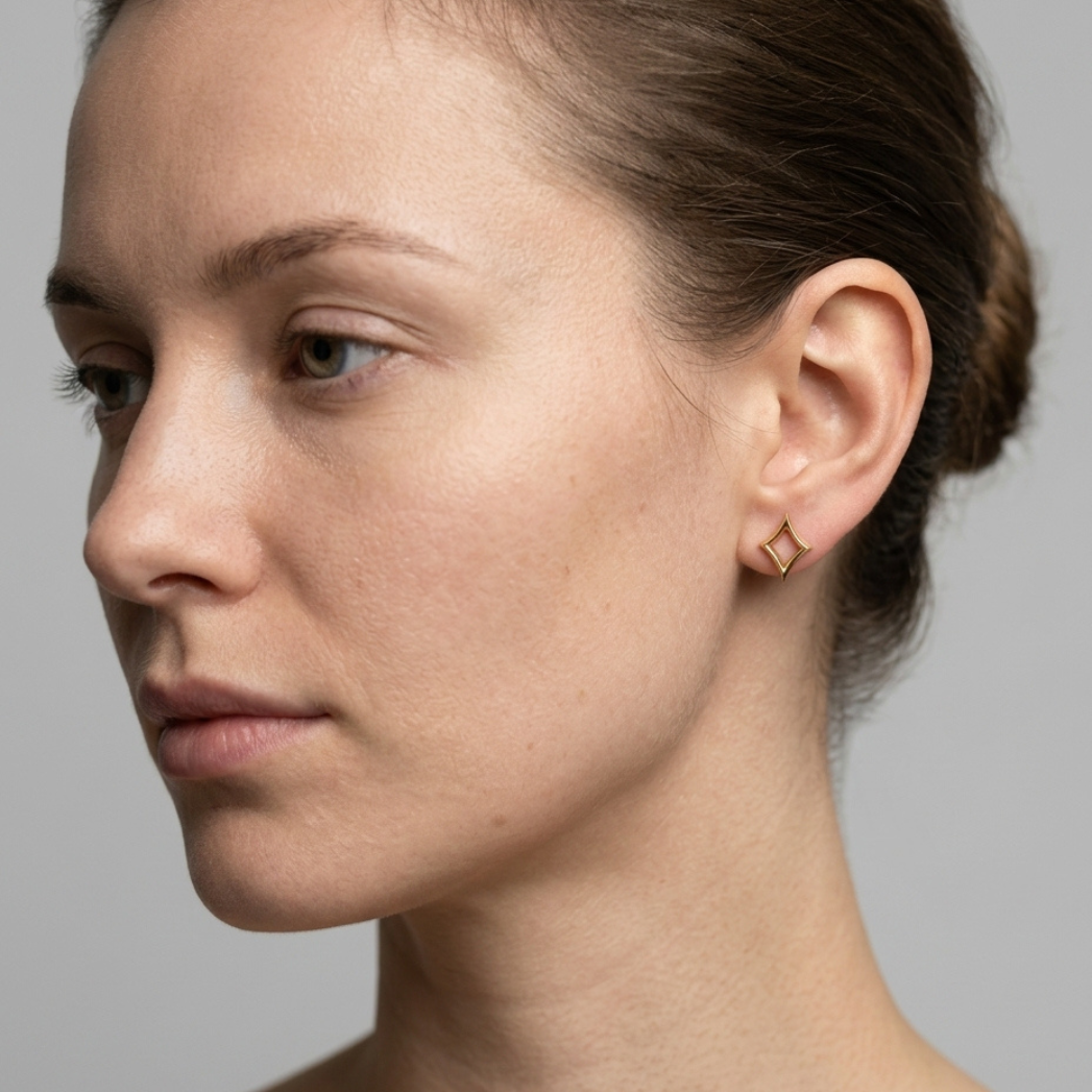 Gold diamond-suit stud earring worn on ear, side profile