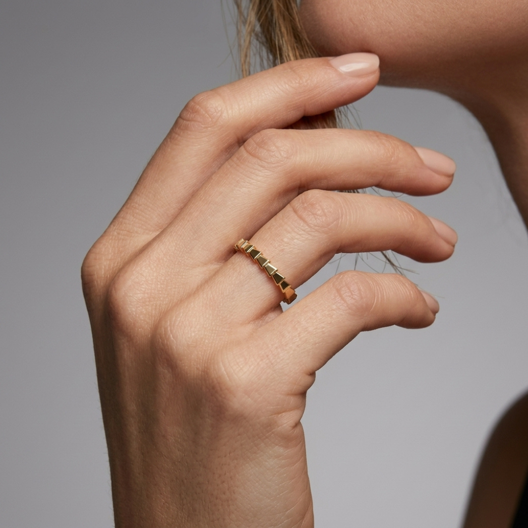 Gold snake-skin textured ring worn on hand, second angle