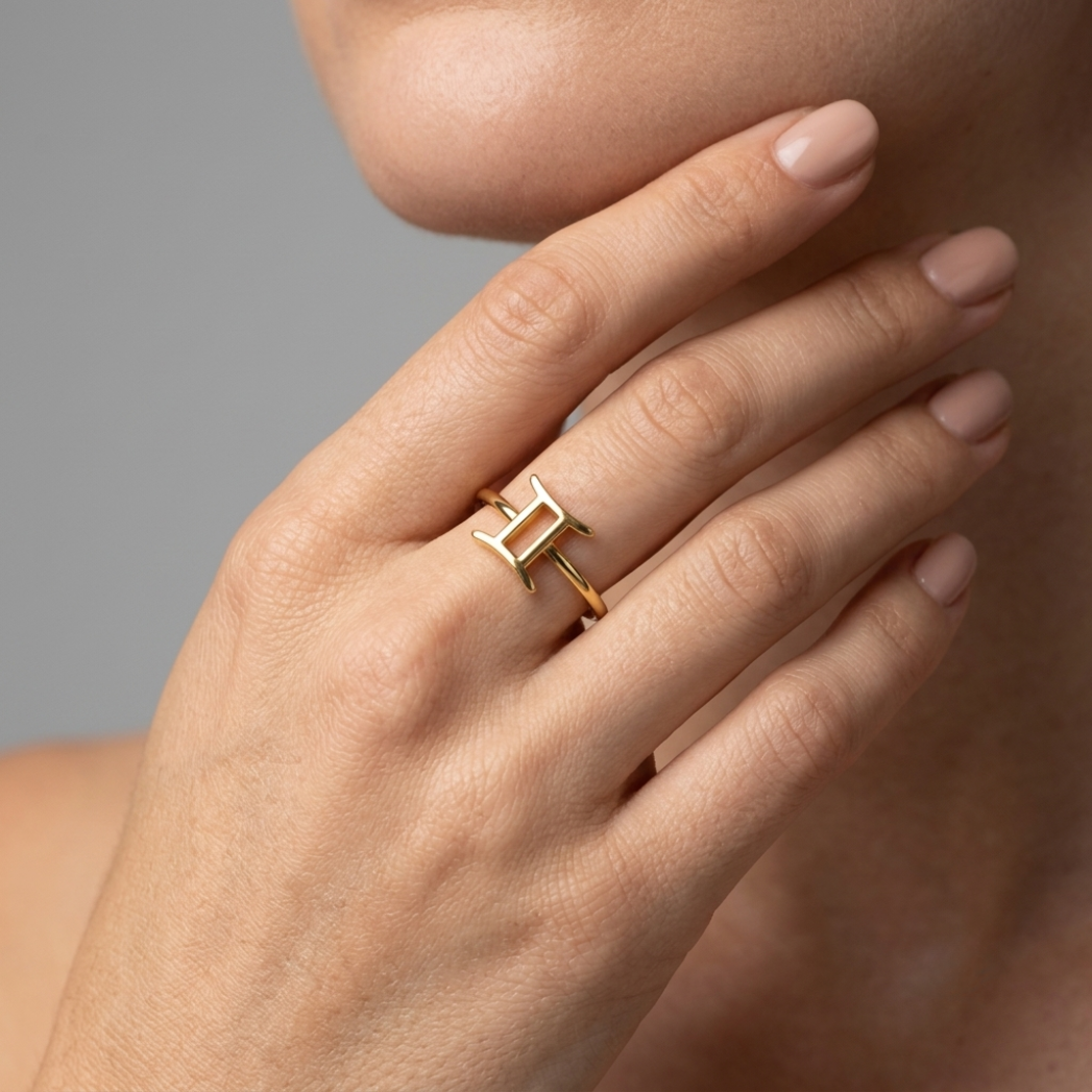 Model's hand resting on fabric wearing Gemini zodiac ring, soft daylight
