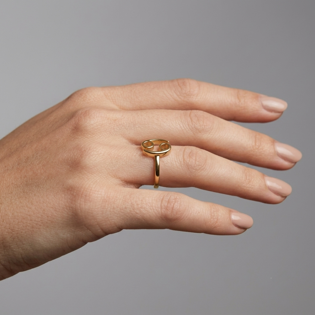 Model wearing Cancer gold ring, editorial close-up on deep charcoal background
