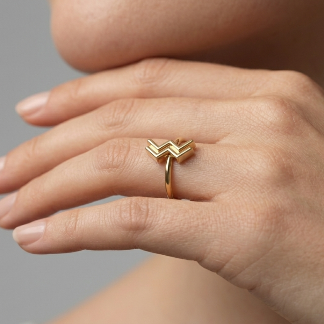 Model wearing Aquarius zodiac gold ring on ring finger, close-up hand shot
