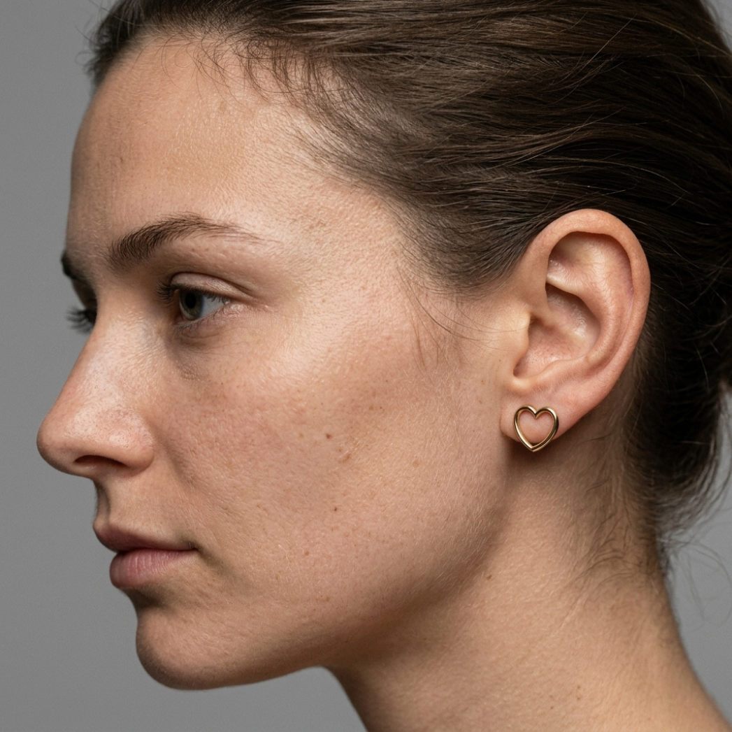 model Pair of gold heart earrings shown on ear, side profile